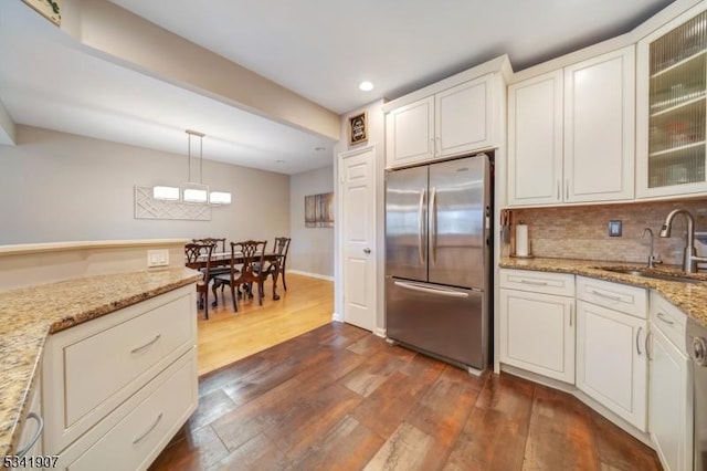 kitchen featuring tasteful backsplash, freestanding refrigerator, dark wood-style flooring, and a sink