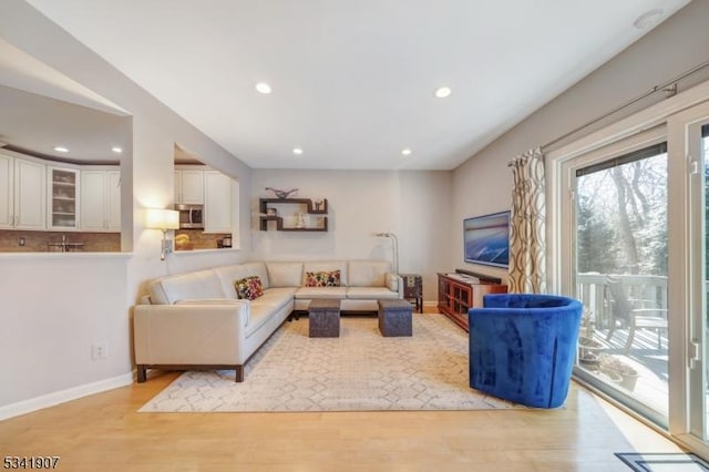 living area featuring light wood-type flooring, baseboards, and recessed lighting