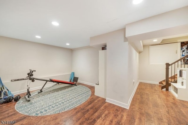 exercise area featuring baseboards, wood finished floors, and recessed lighting