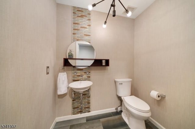 half bath featuring toilet, baseboards, and visible vents