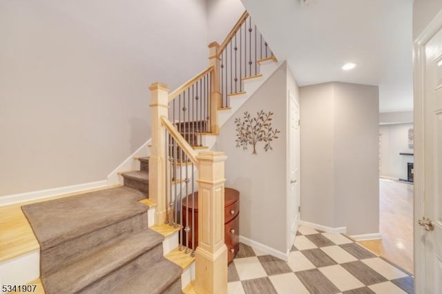 staircase featuring recessed lighting, a fireplace, baseboards, and tile patterned floors