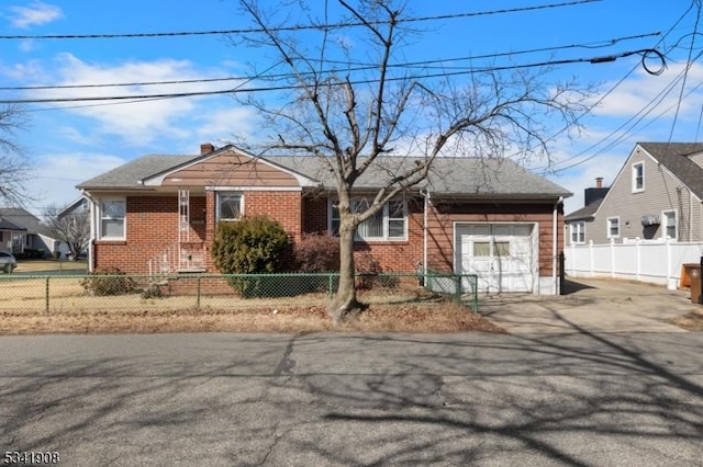 view of front of property featuring a garage, driveway, a fenced front yard, and brick siding