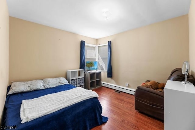 bedroom with a baseboard radiator and wood finished floors