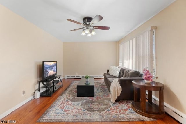 living area with a baseboard heating unit, wood finished floors, a ceiling fan, and baseboards