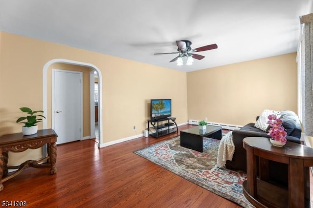 living room with arched walkways, a baseboard radiator, a ceiling fan, wood finished floors, and baseboards