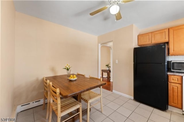 dining area featuring a ceiling fan, arched walkways, baseboards, and light tile patterned floors