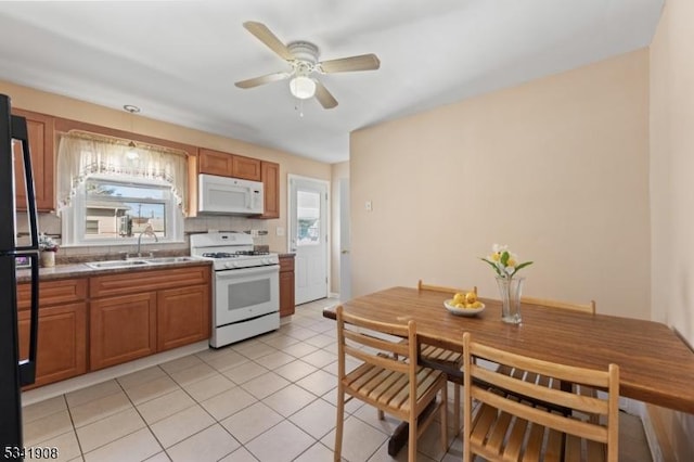 kitchen with white appliances, plenty of natural light, brown cabinetry, and a sink