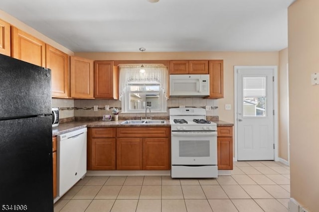 kitchen featuring white appliances, decorative backsplash, a sink, and a healthy amount of sunlight