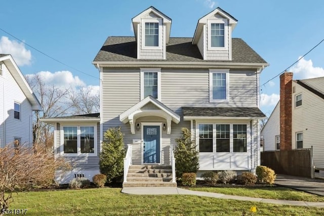 view of front of property featuring roof with shingles and a front yard