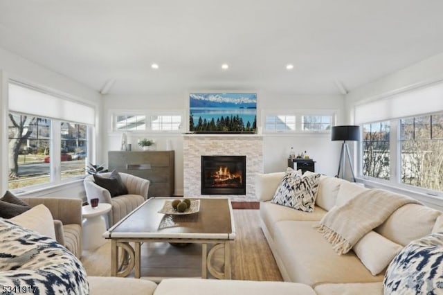 living room featuring recessed lighting, wood finished floors, and a stone fireplace