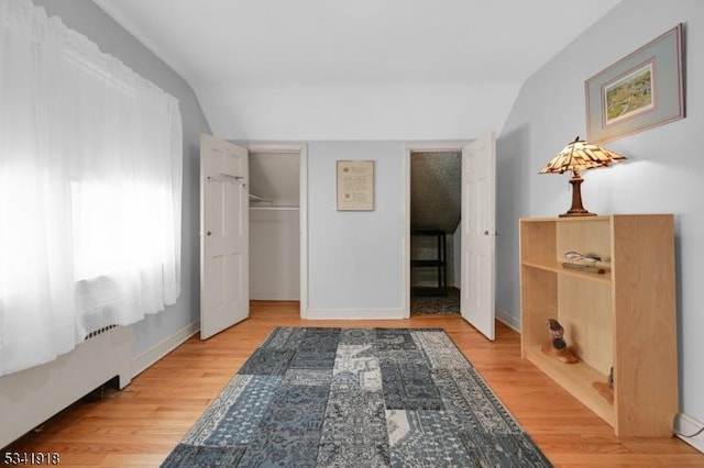 bedroom featuring light wood-style floors, baseboards, and vaulted ceiling