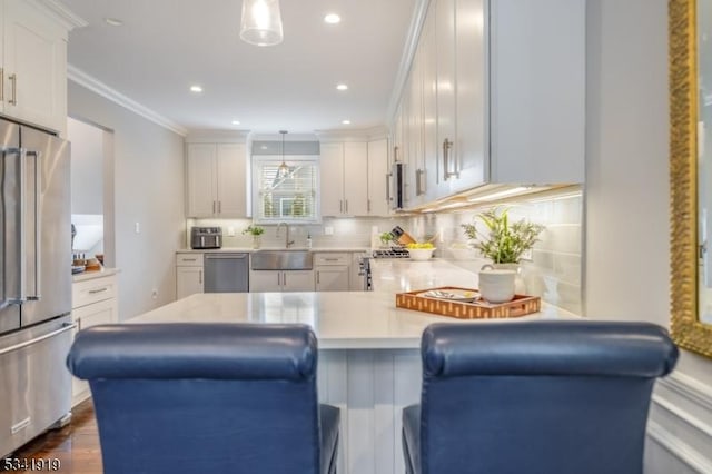 kitchen with crown molding, light countertops, decorative backsplash, appliances with stainless steel finishes, and a sink