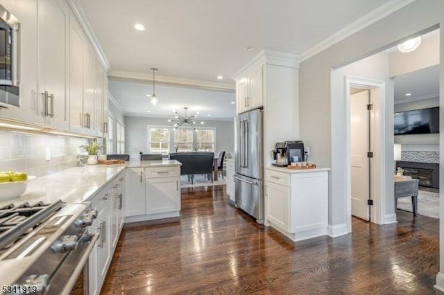 kitchen with premium appliances, a peninsula, dark wood-style flooring, white cabinetry, and ornamental molding