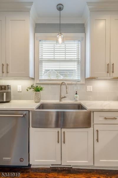 kitchen with stainless steel dishwasher, a sink, white cabinetry, and crown molding