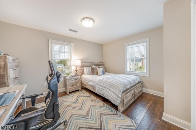 bedroom with baseboards, multiple windows, visible vents, and hardwood / wood-style floors