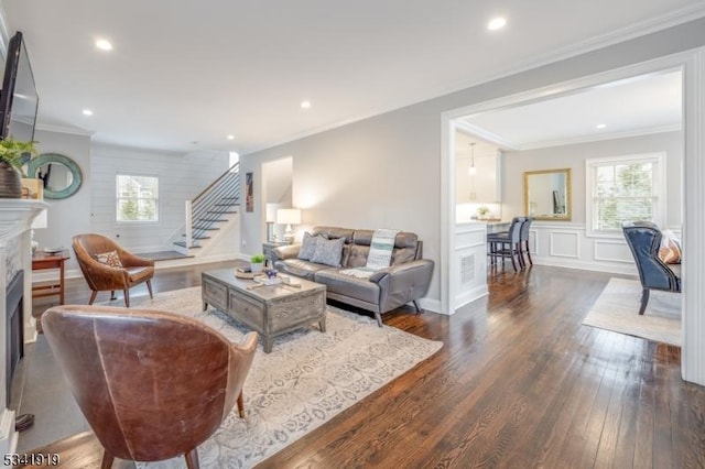 living room featuring recessed lighting, a fireplace, stairs, ornamental molding, and dark wood-style floors