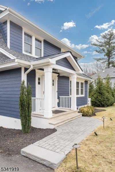 property entrance with covered porch and roof with shingles