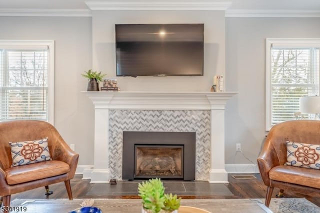 living room with baseboards, a fireplace, wood finished floors, and crown molding