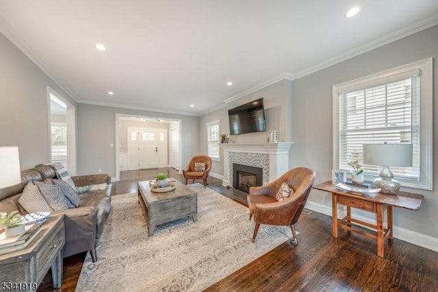 living room with wood finished floors, plenty of natural light, a tile fireplace, and crown molding