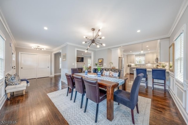 dining space featuring ornamental molding, dark wood-style flooring, and an inviting chandelier