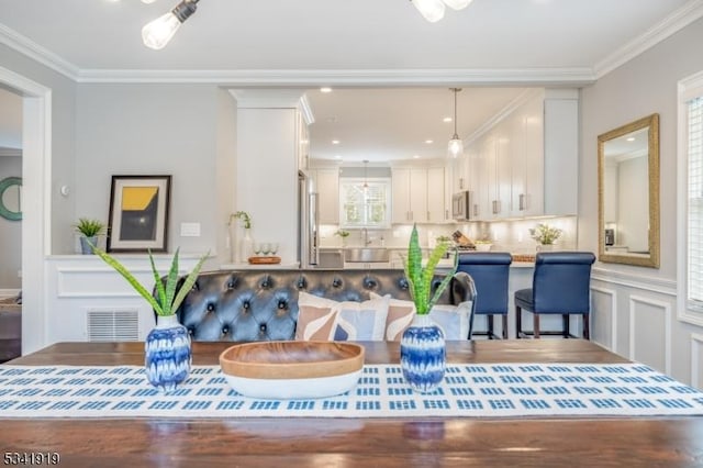 rec room with ornamental molding, a sink, visible vents, and a decorative wall