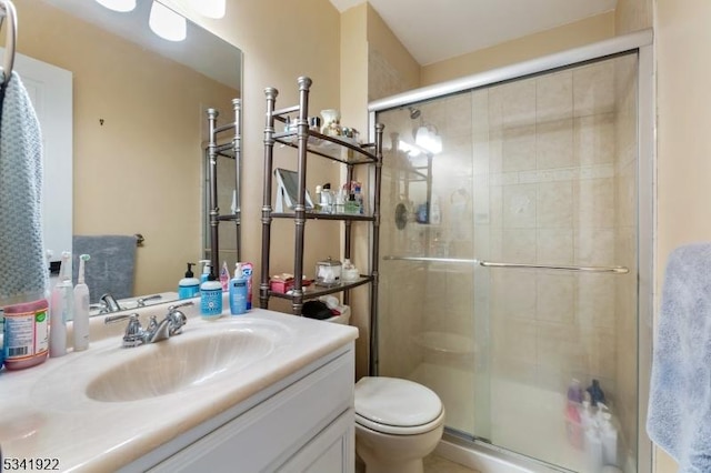 bathroom with vanity, a shower stall, and toilet