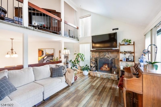 living room with wood finished floors, high vaulted ceiling, a chandelier, and a fireplace