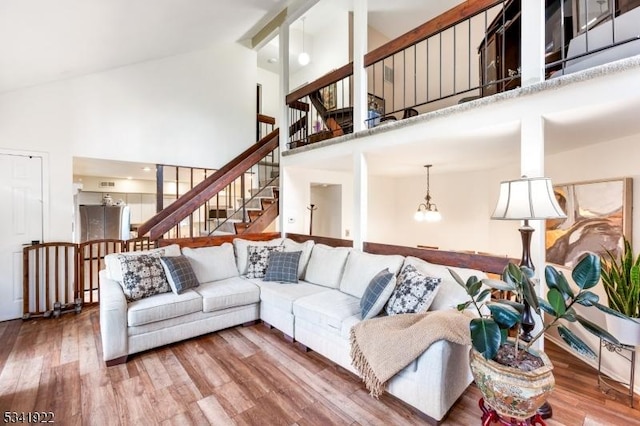 living area with stairs, wood finished floors, and high vaulted ceiling