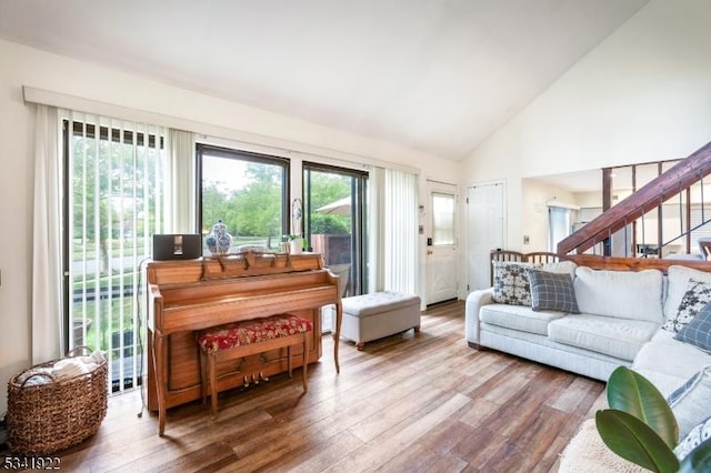 living room featuring high vaulted ceiling, wood finished floors, and stairs