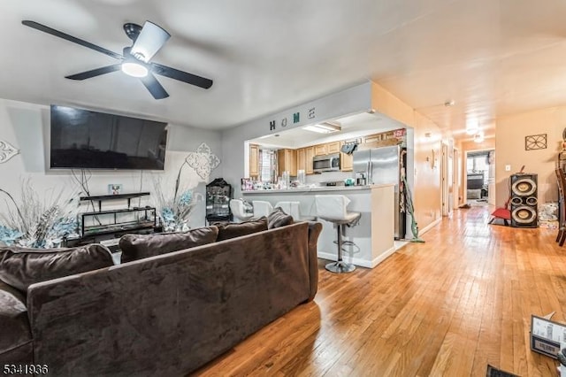 living area featuring light wood-style flooring and ceiling fan