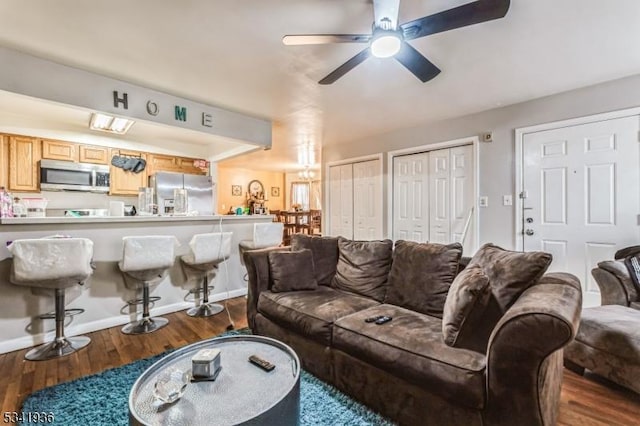 living room featuring ceiling fan, wood finished floors, and baseboards