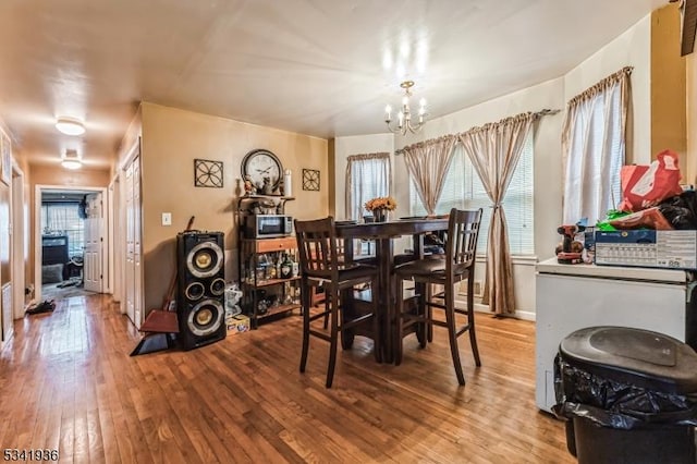 dining area featuring baseboards, an inviting chandelier, and light wood-style floors