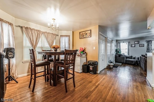 dining space featuring baseboards, wood-type flooring, and an inviting chandelier