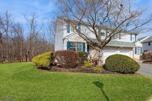 traditional home featuring aphalt driveway, a garage, brick siding, and a front lawn