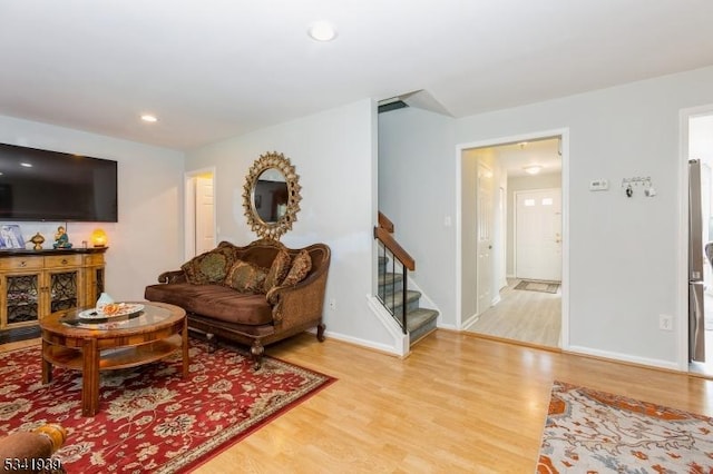 living room with light wood finished floors, stairs, baseboards, and recessed lighting