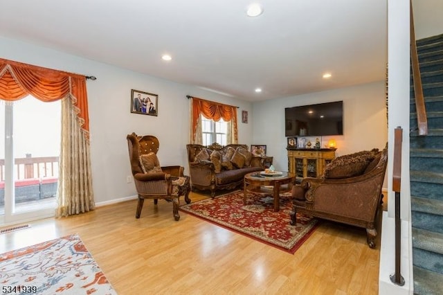 living room featuring recessed lighting, visible vents, baseboards, stairway, and light wood finished floors