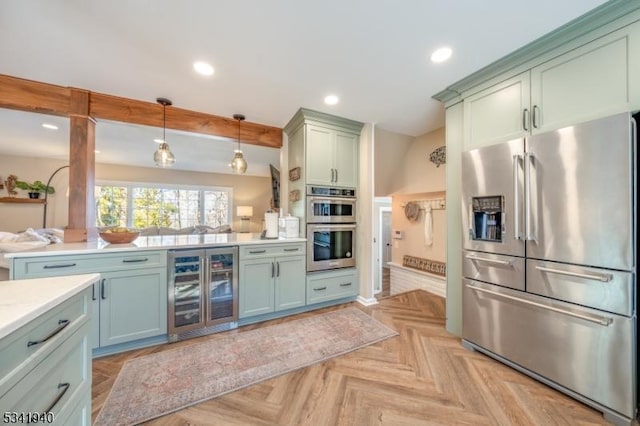 kitchen with beverage cooler, appliances with stainless steel finishes, light countertops, green cabinetry, and recessed lighting