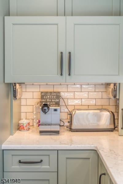 interior details featuring light stone countertops, decorative backsplash, and gray cabinetry