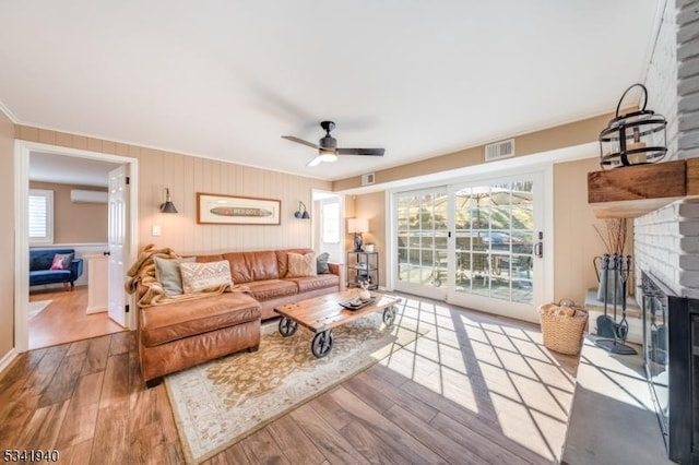 living room featuring a wealth of natural light, a fireplace, wood finished floors, and visible vents