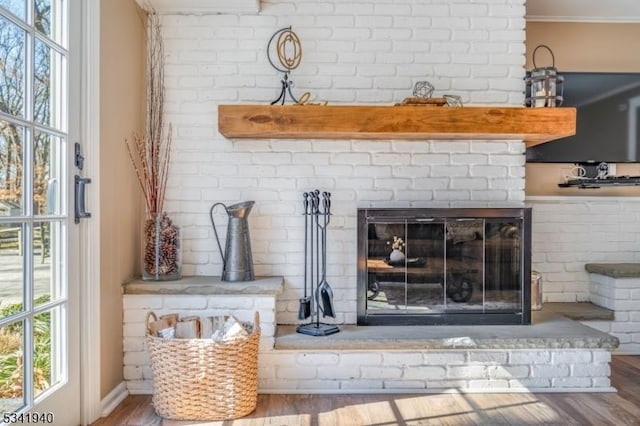 room details with a brick fireplace, wood finished floors, and crown molding