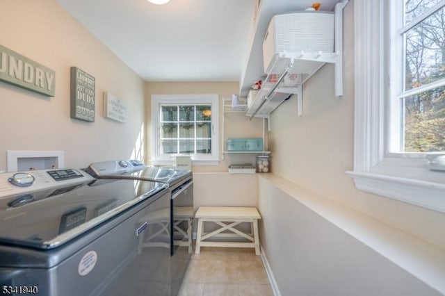 washroom with light tile patterned floors, laundry area, separate washer and dryer, and baseboards