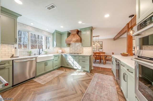 kitchen featuring visible vents, green cabinetry, appliances with stainless steel finishes, premium range hood, and a sink