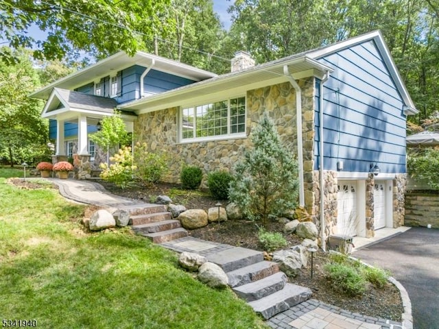 view of front of house with a garage, driveway, a chimney, and stone siding