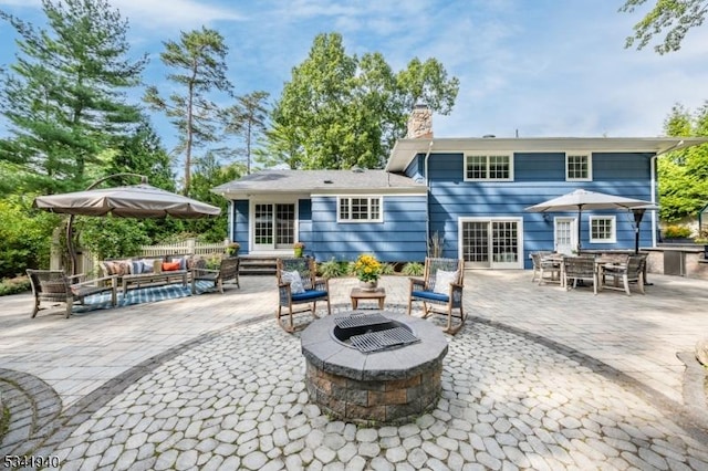 back of house featuring a chimney, a patio area, and an outdoor living space with a fire pit