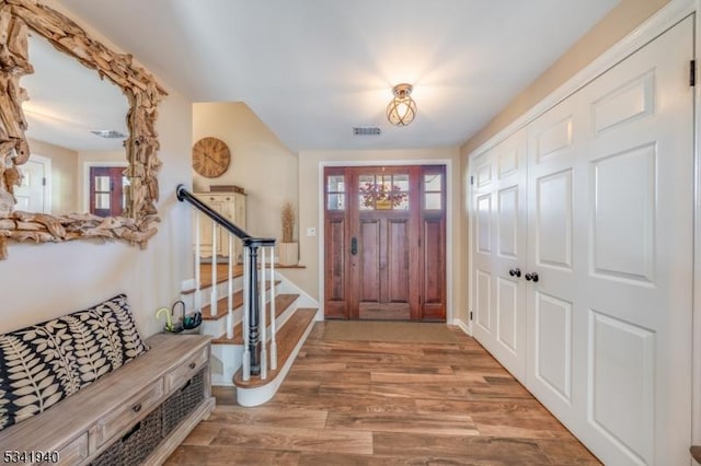 foyer entrance featuring stairs, visible vents, and wood finished floors