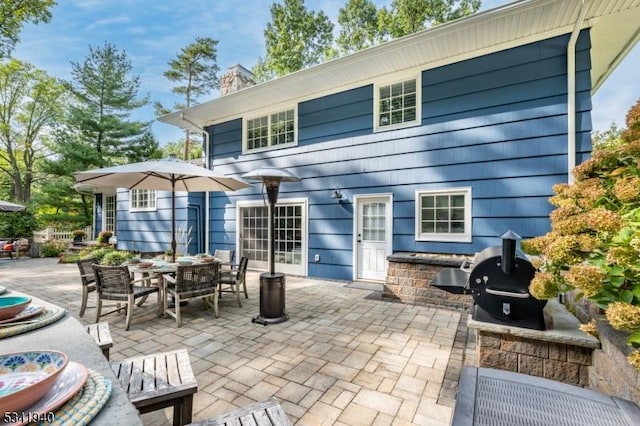 back of house with outdoor dining space, a chimney, and a patio