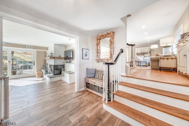 stairway with a brick fireplace, visible vents, and wood finished floors