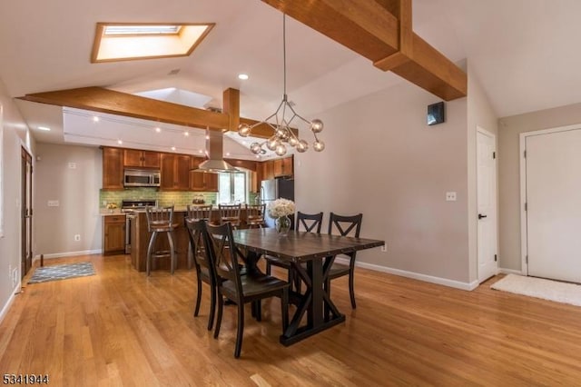 dining space featuring light wood-type flooring, lofted ceiling with skylight, baseboards, and an inviting chandelier