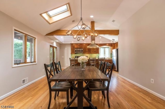 dining room featuring lofted ceiling with skylight, light wood-style flooring, baseboards, and visible vents