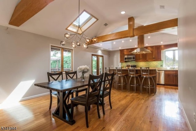 dining room with recessed lighting, baseboards, vaulted ceiling with skylight, and light wood finished floors